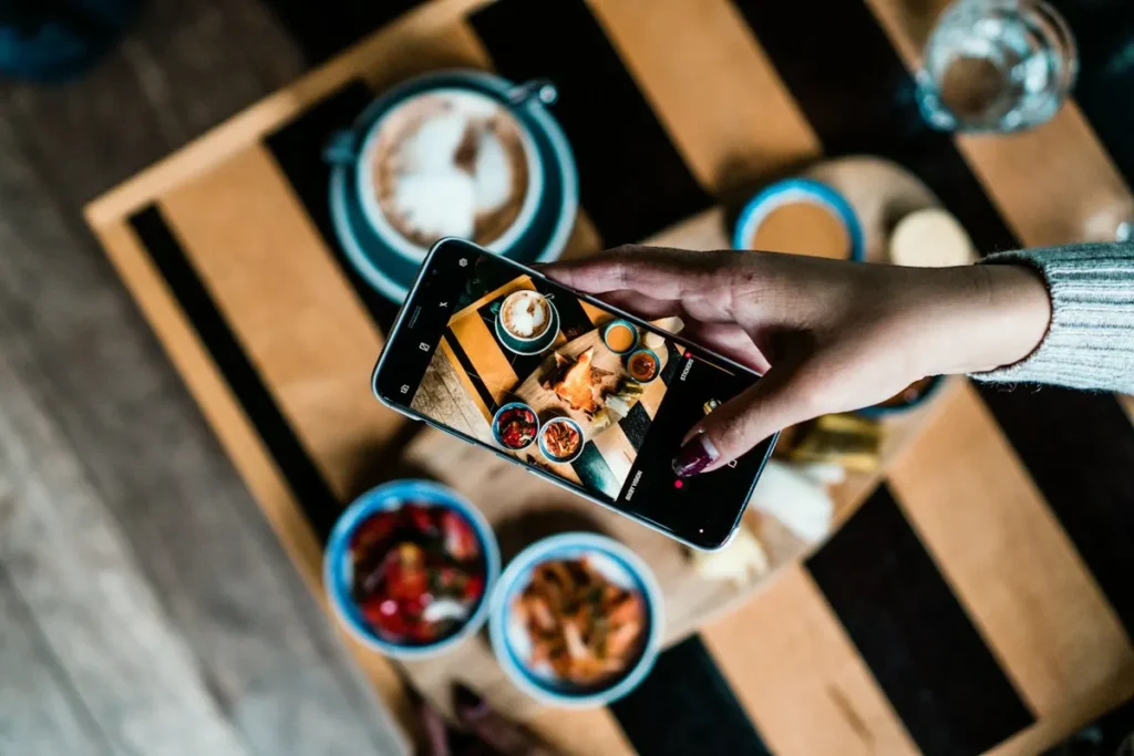 Persona fotografiando un plato con el móvil: fotografía profesional o móvil